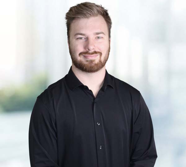 Professional portrait of a smiling man in a black shirt, representing the team at Practical Metals, highlighting leadership in metal construction solutions.