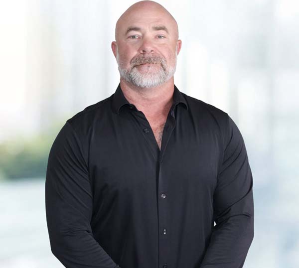 Chance Roberts, Co-Founder and President of Practical Metals, standing confidently in a black shirt, with a blurred background suggesting a professional environment.