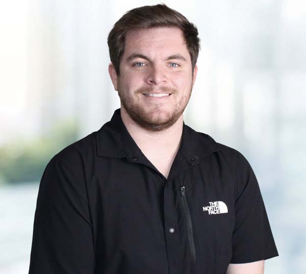 Man smiling in a black The North Face shirt, representing the team at Practical Metals, showcasing leadership and commitment to quality in metal construction.
