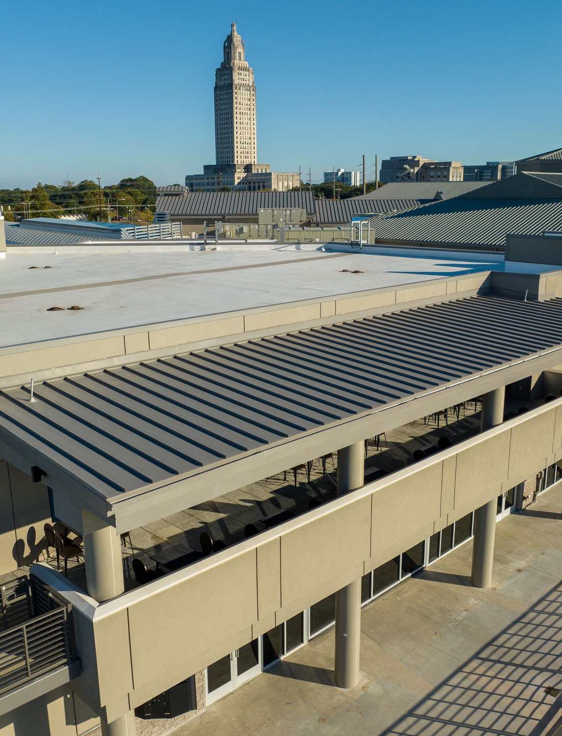 Roofing system with modern metal panels and architectural design, featuring a view of a tall building in the background, emphasizing Practical Metals' solutions for construction in South Central US.